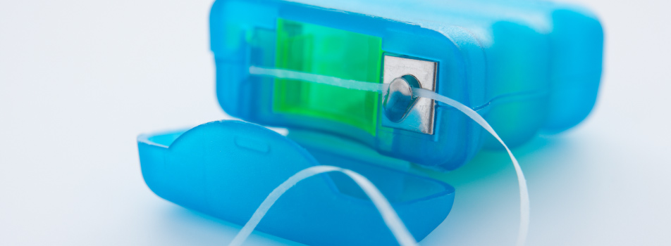 blue container of string dental floss sitting on a white countertop