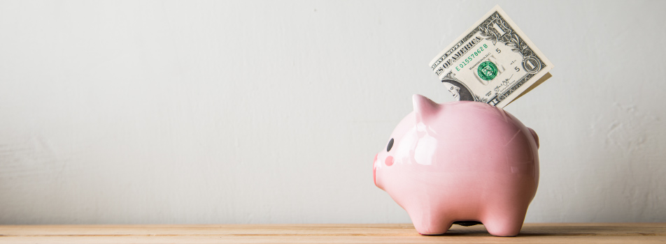 A one dollar bill rests on top of a pink piggy bank used for saving money after receiving affordable dental care