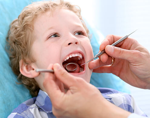 young boy having his teeth examined