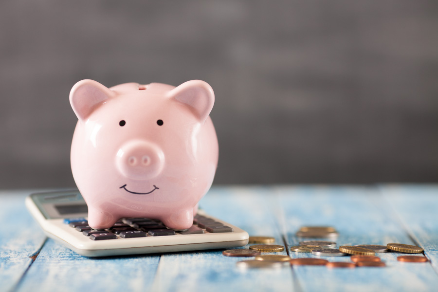 Closeup of piggy bank on a calculator next to coins for affordable dental care without insurance