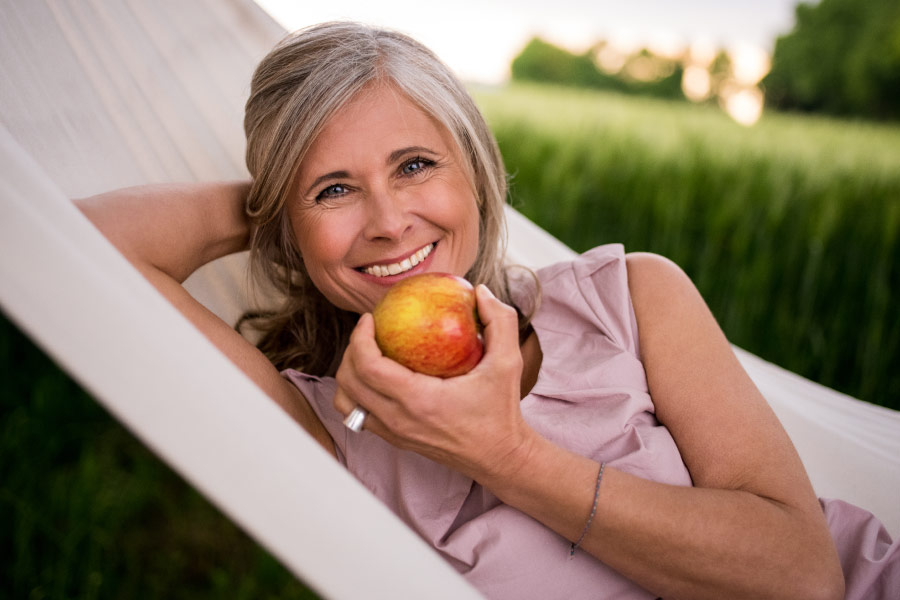 Middle-aged woman snacks on an apple during the COVID-19 pandemic stay at home order in a hammock in Austin, TX
