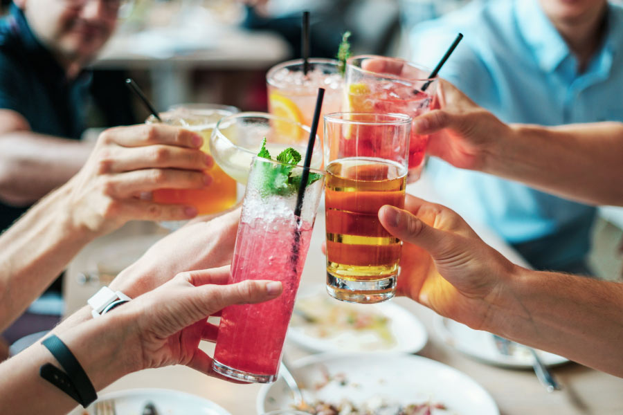 A group of people touch their alcohol drinks together at the table