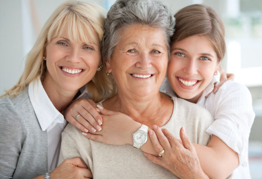 Three generations of women smile after restoring their smiles with dental bridges and dental crowns