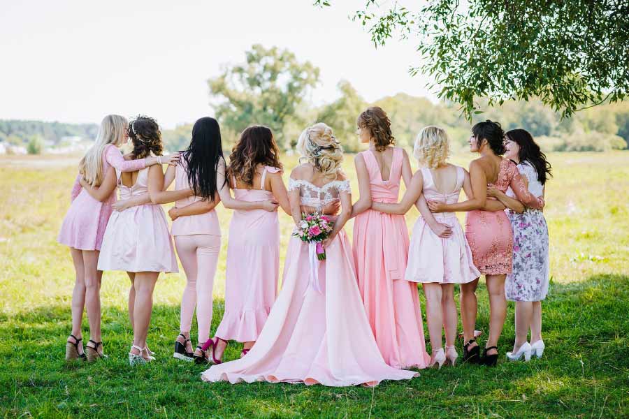 Rear view of a wedding line with the bride surrounded by her attendants dressed in pink.