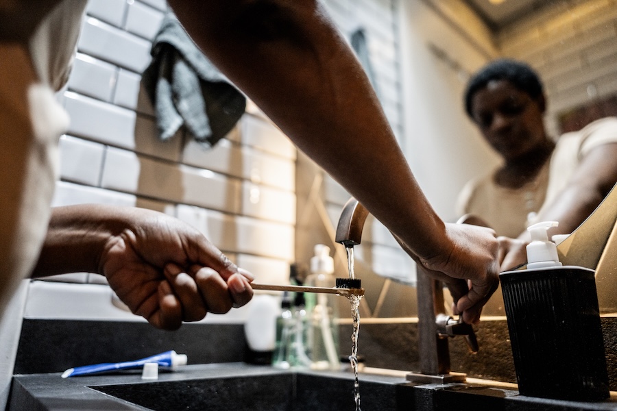 Black woman brushing teeth in a sink that may have hard water